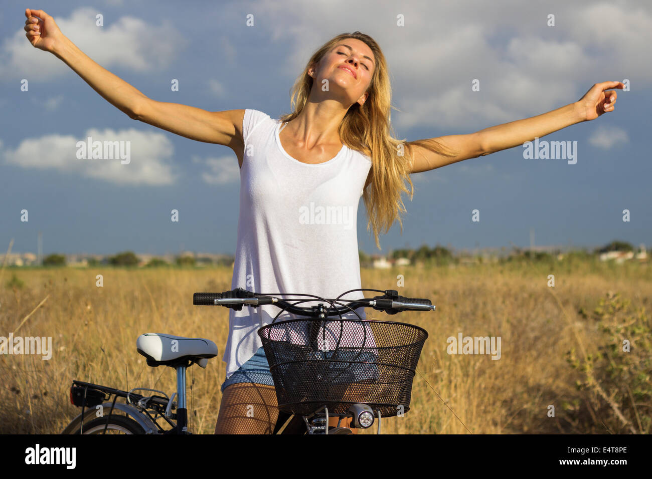 Giovane bella ragazza bionda donna rilassante libertà gratuito bicicletta campagna natura outdoor bellezza naturale 't-shirt bianco' Foto Stock