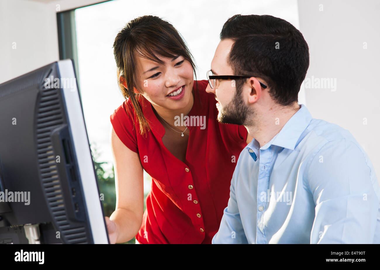 Close-up del giovane imprenditore e giovane imprenditrice avente una discussione di fronte a un computer in ufficio, Germania Foto Stock