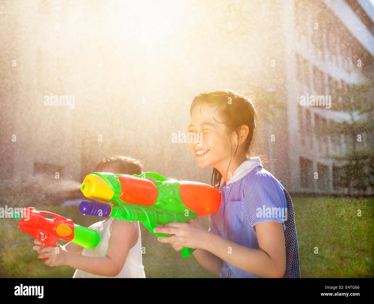 Allegro ragazze giochi d'acqua pistole nel parco Foto Stock