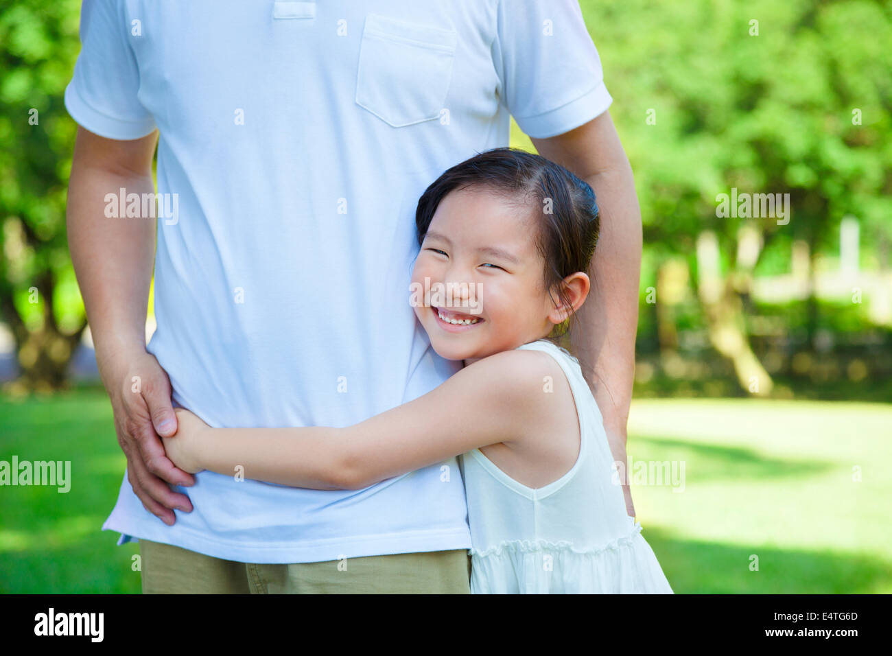 Sorridente bambina abbraccio padre vita nel parco Foto Stock