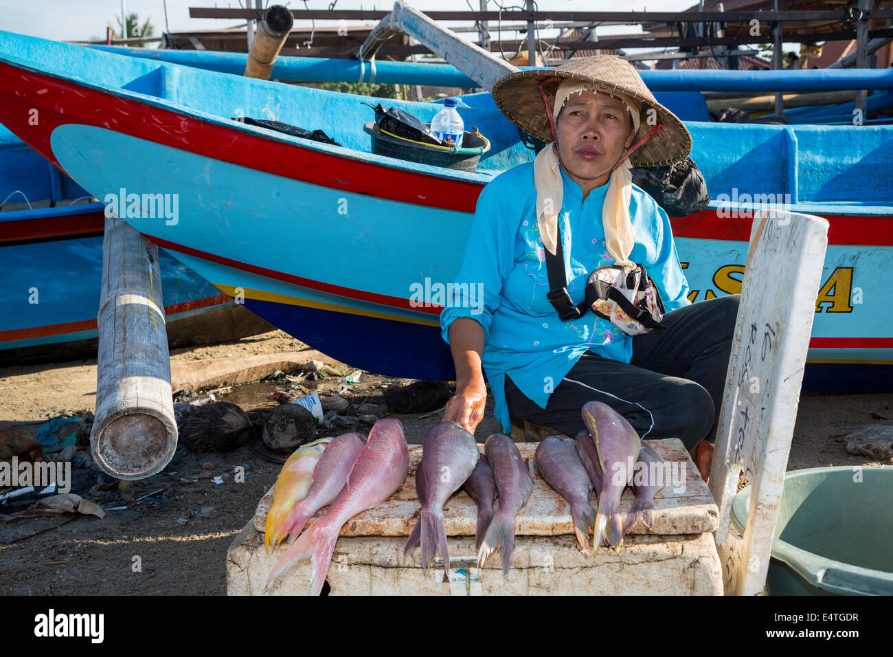 Spiaggia di Jimbaran, Bali, Indonesia. Donna di vendita del pesce sulla spiaggia di mattina presto. Foto Stock
