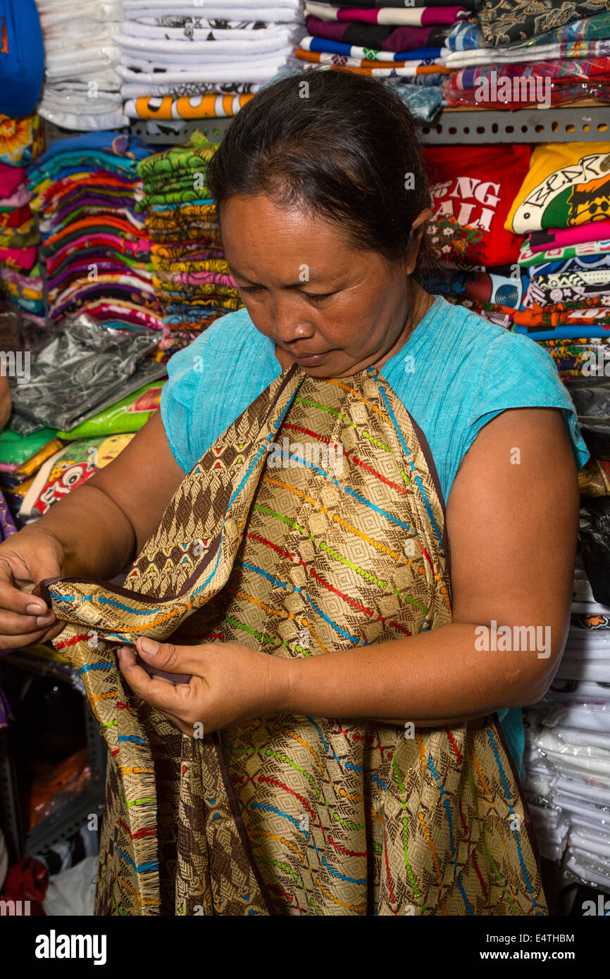 Sukawati, Bali, Indonesia. Negoziante il ripiegamento di un sarong. Foto Stock