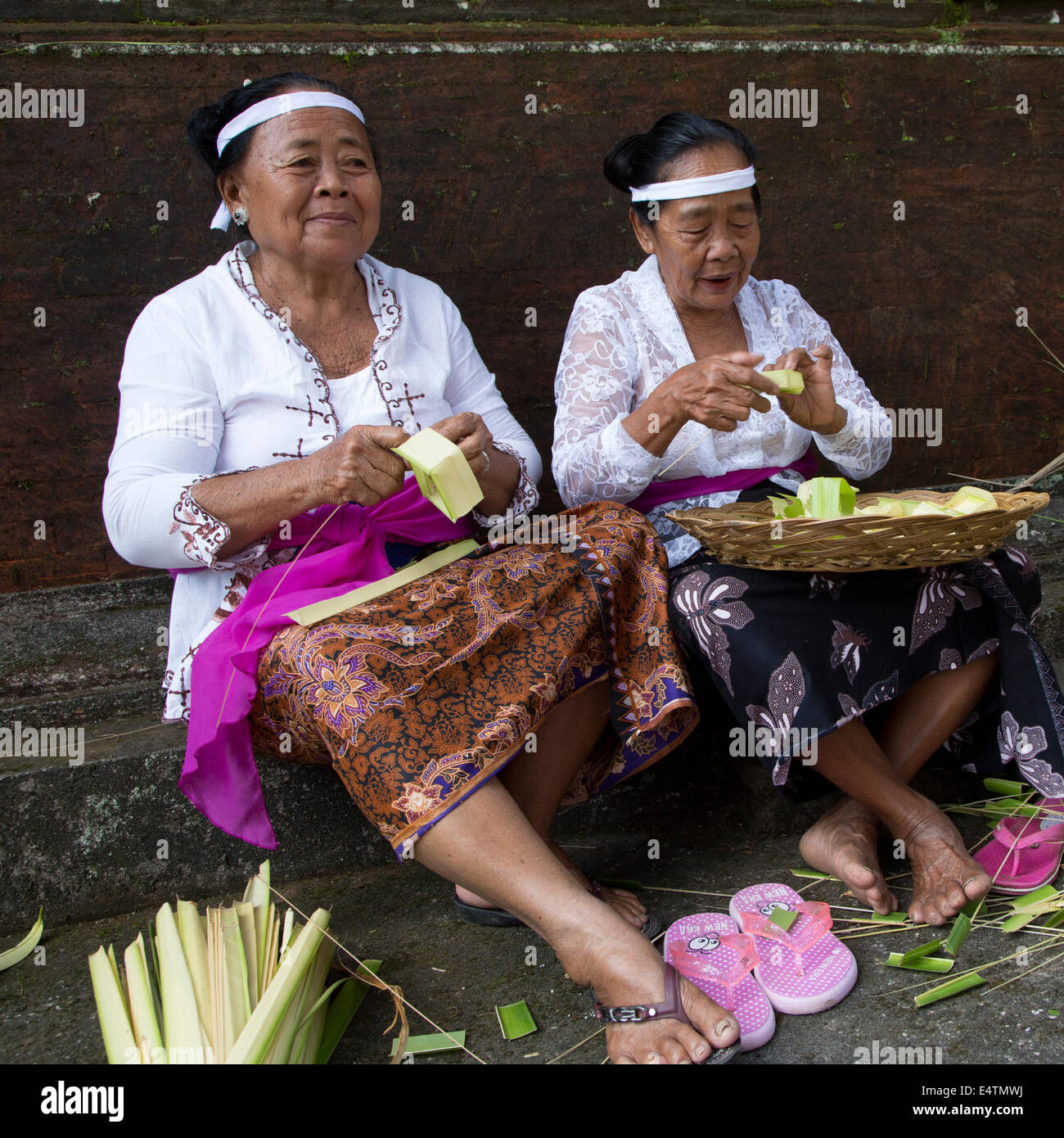 Bali, Indonesia. Balinese donne Indù rendendo offrendo cestini (Canang) da fronde di palma. Foto Stock