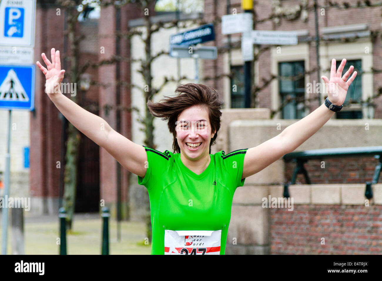 Dordrecht, Netherlands-April 6, 2014: Femmina runner in verde per celebrare durante la sessantasettesima edizione della porta Dwars Dordt, un comp Foto Stock