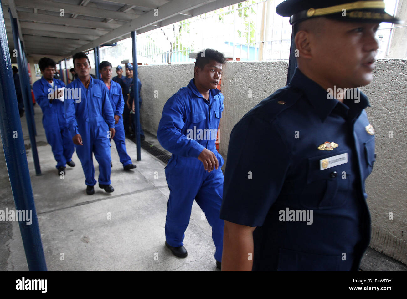 Manila, Filippine. 17 Luglio, 2014. Un membro del Philippine Coast Guard (PCG) conduce i quattro soccorse i pescatori filippino all'interno di PCG sede a Manila nelle Filippine, il 17 luglio 2014. L'equipaggio della nave cinese MV Pacific Pioneer, che proveniva da Hong Kong della Repubblica popolare cinese, ha salvato il quattro pescatori filippini che erano in mare per due giorni dopo la loro nave è stato immerso in un forte vento ha portato dal tifone Rammasun. © Rouelle Umali/Xinhua/Alamy Live News Foto Stock