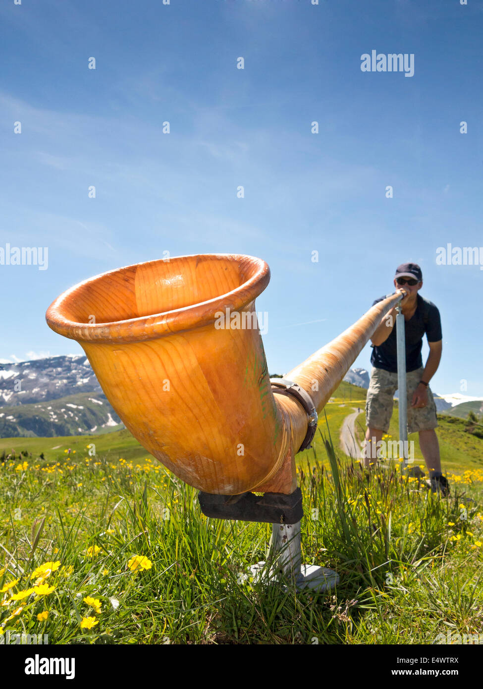 Angolo basso punto di vista di un uomo la riproduzione di un'alphorn nelle alpi svizzere Foto Stock