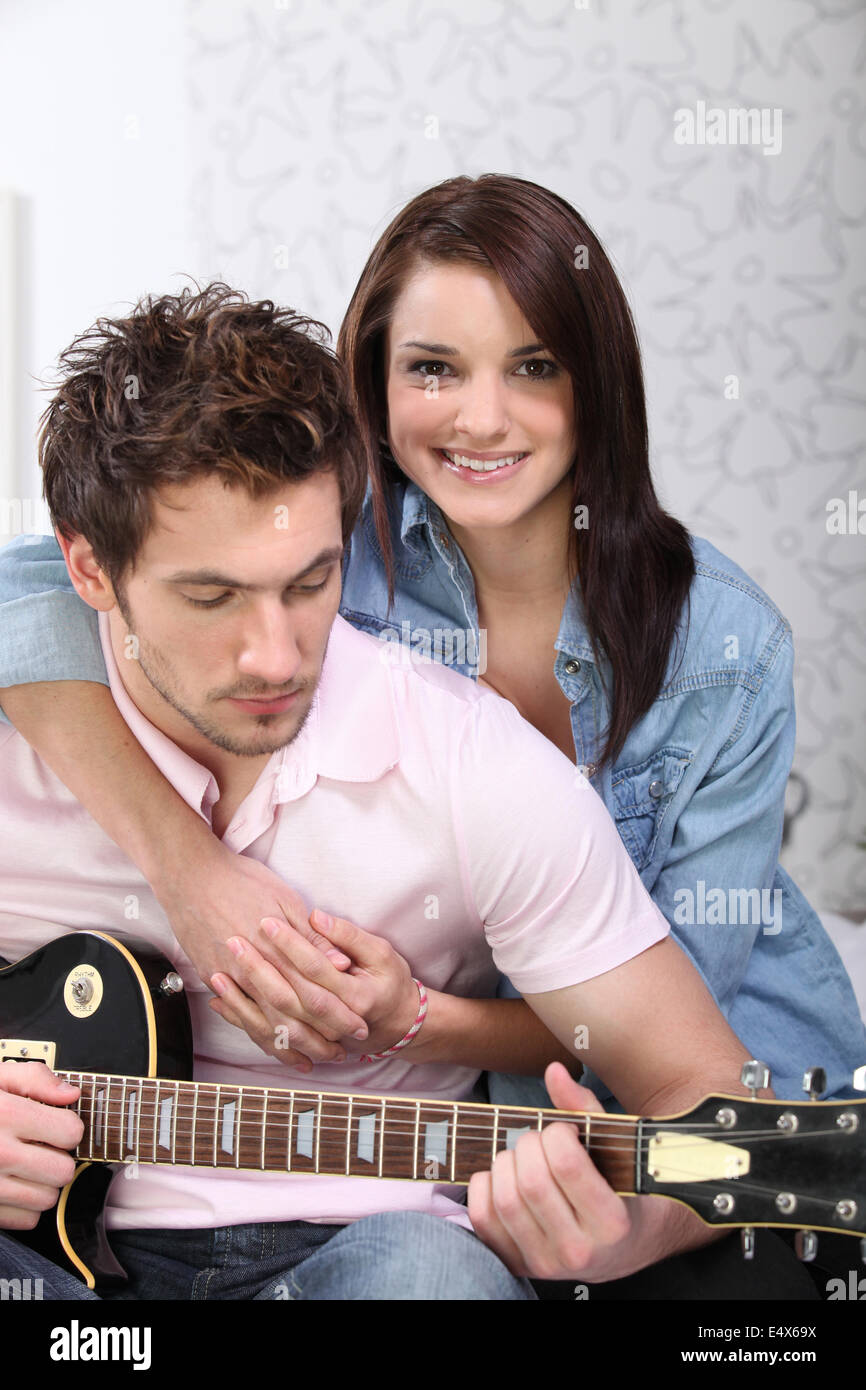 Coppia giovane di suonare una chitarra a casa Foto Stock