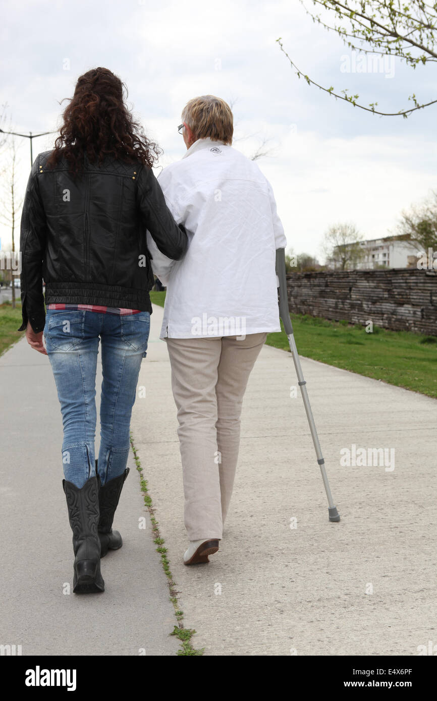 Giovane donna aiutando anziana signora a piedi Foto Stock