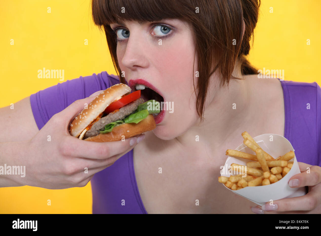 Donna di mangiare hamburger e patatine fritte Foto Stock