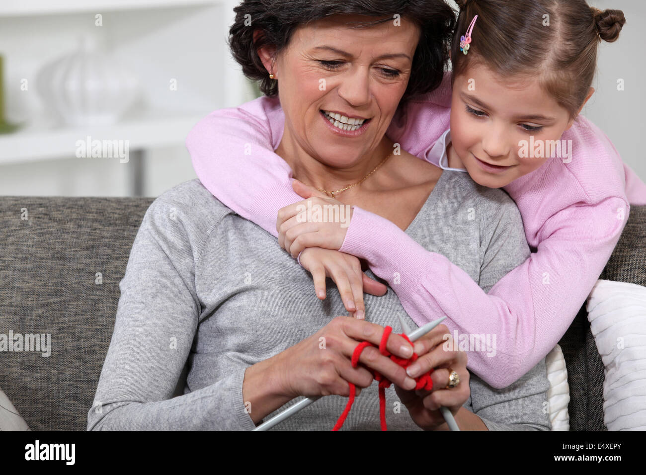 Una mamma che mostra il modo di lavorare a maglia di sua figlia. Foto Stock