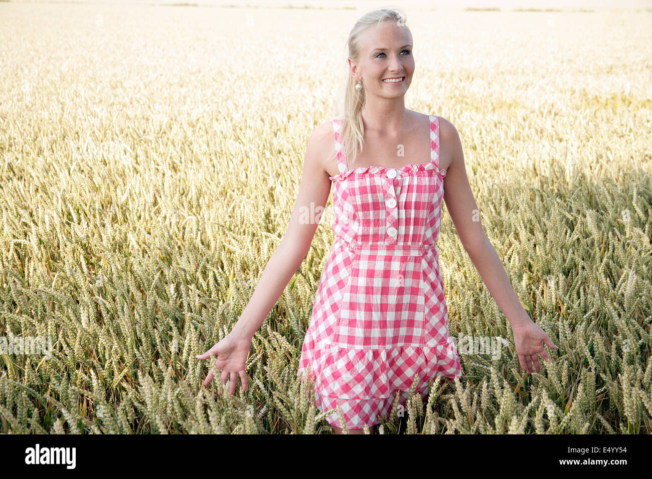 Giovane donna a piedi attraverso un campo di grano Foto Stock
