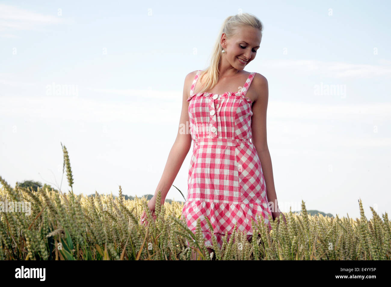 Giovane donna a piedi attraverso un campo di grano Foto Stock