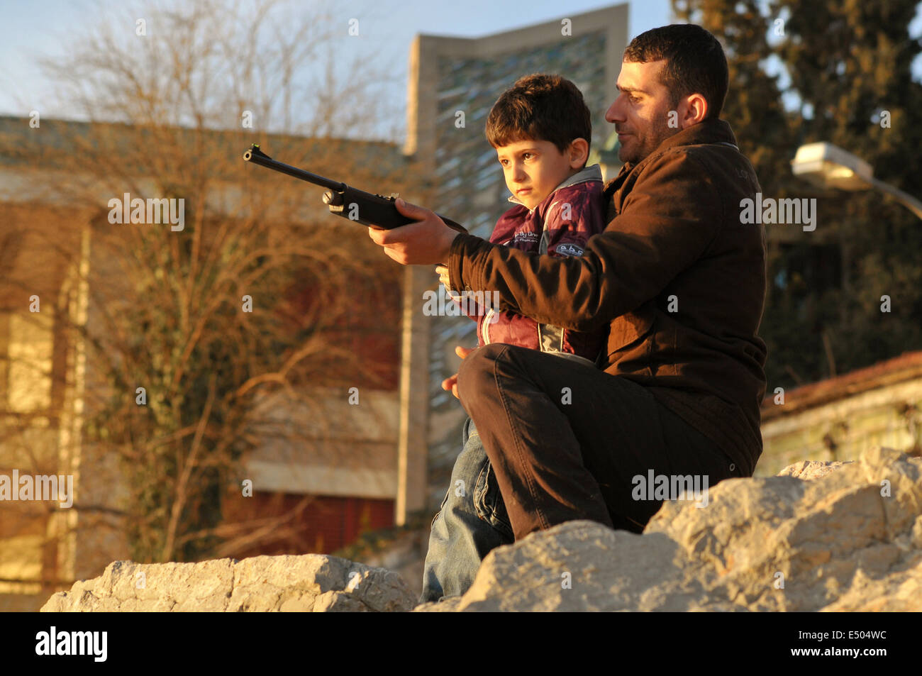 Un uomo turco e un ragazzino sta giocando con un fucile ad aria compressa. Improvvisato gallerie di tiro sono popolari con i passanti lungo th Foto Stock