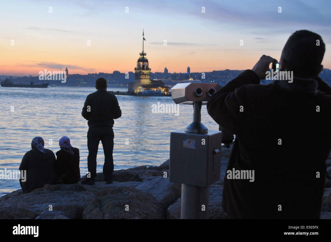 Popolo turco relax sul lungomare di Üsküdar al tramonto. Maiden's Tower (K?z Kulesi) può essere visto in background. Foto Stock