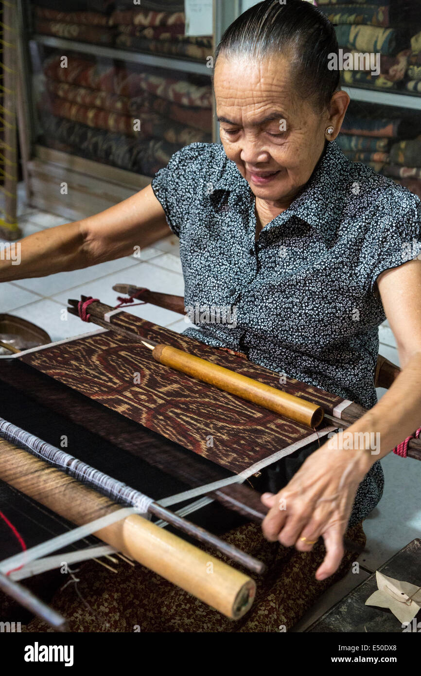 Bali, Indonesia. La donna la tessitura utilizzando Back-fascetta telaio per la tessitura Geringsing panno, una specialità del villaggio di Tenganan. Foto Stock