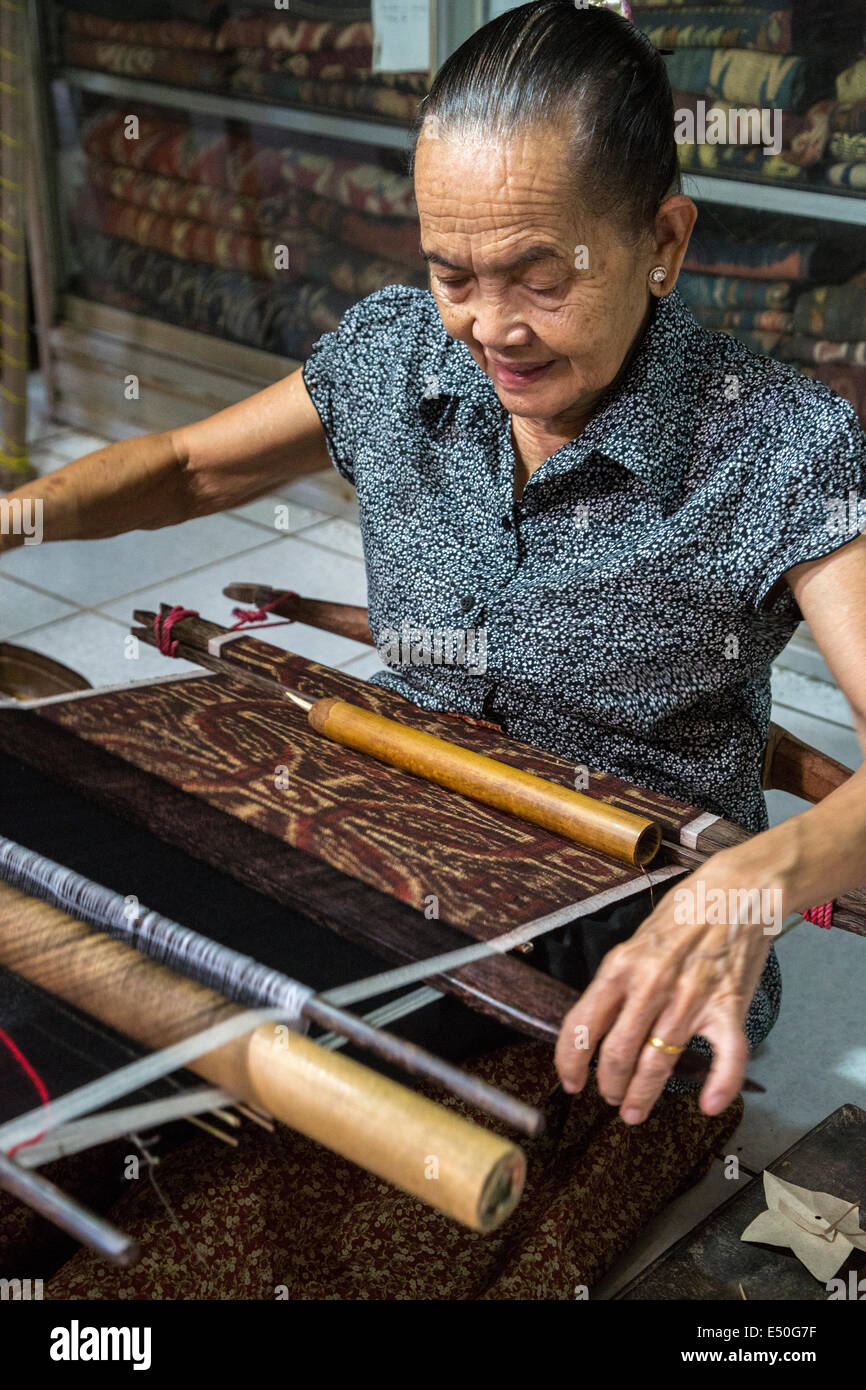 Bali, Indonesia. La donna la tessitura utilizzando Back-fascetta telaio per la tessitura Geringsing panno, una specialità del villaggio di Tenganan. Foto Stock