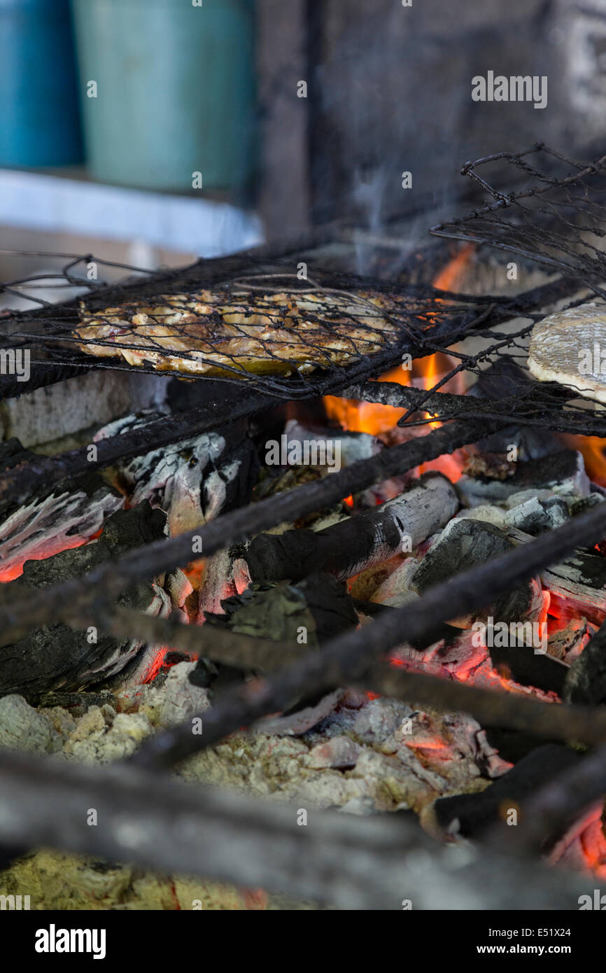 Bali, Indonesia. Grigliare il pesce su un fuoco di carbone in un piccolo Fast Food Stand in Jimbaran Mercato del Pesce. Foto Stock
