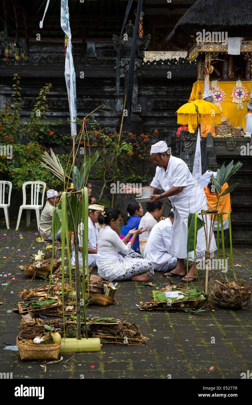 Jatiluwih, Bali, Indonesia. Un sacerdote spruzza acqua santa su adoratori al Luhur Bhujangga Waisnawa tempio indù. Foto Stock