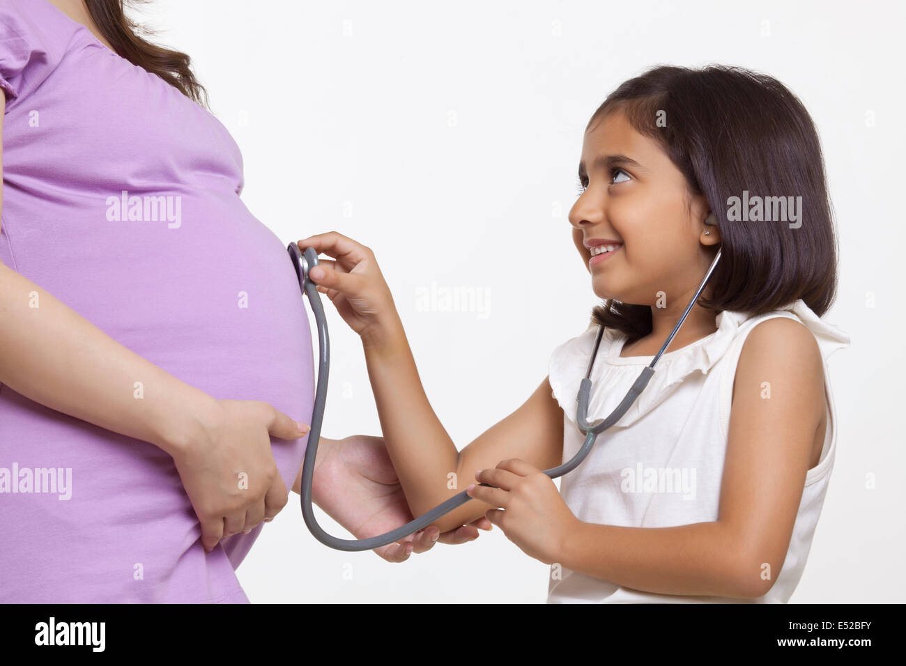 Figlia di uno stetoscopio di contenimento a donne in stato di gravidanza della madre stomaco Foto Stock