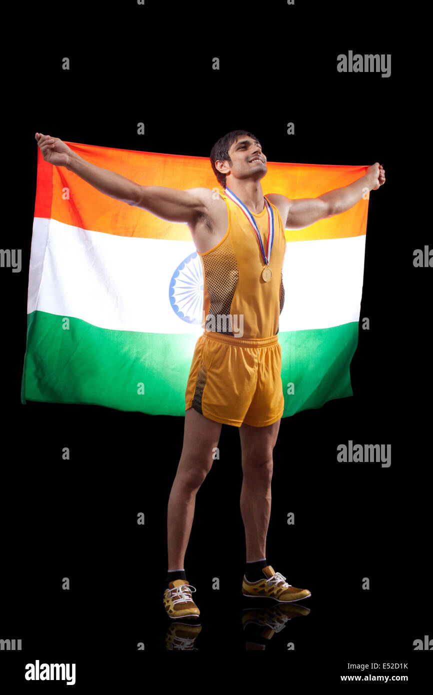Lunghezza completa di felice medaglia maschio con bandiera indiana cercando su sfondo nero Foto Stock