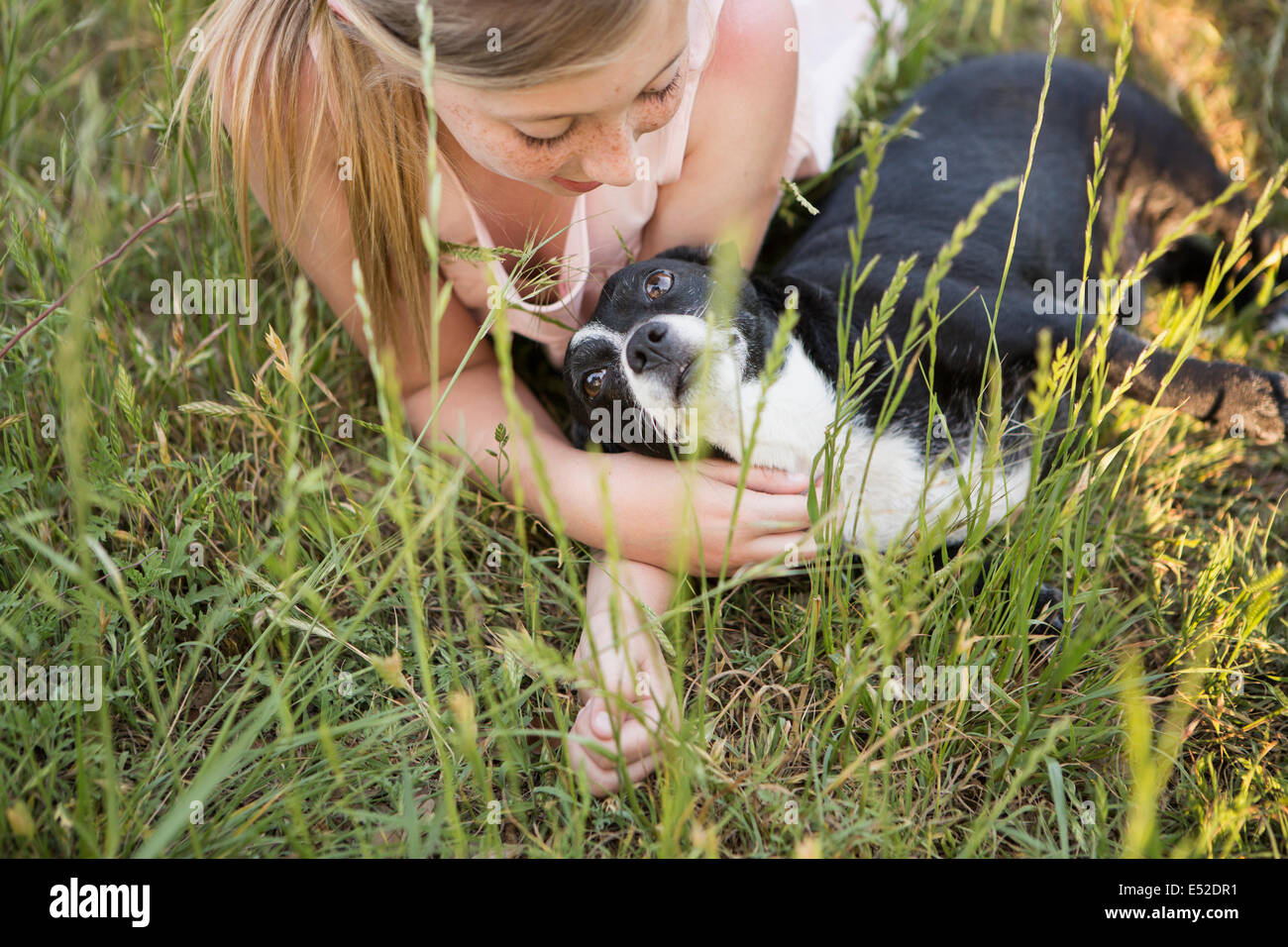 Una ragazza che abbraccia un bianco e nero cane nel parco. Foto Stock