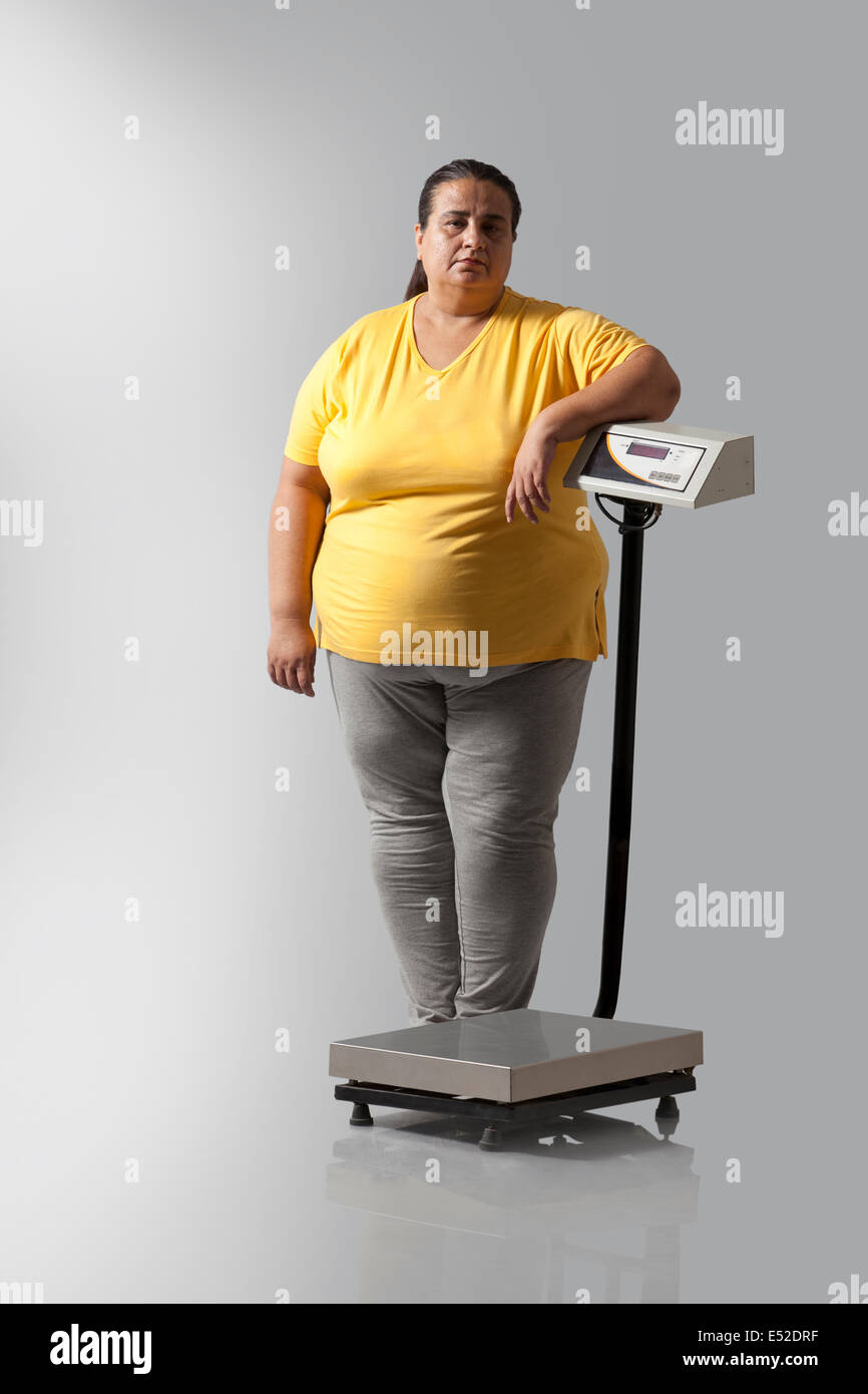 Ritratto di donna obesa con scala di pesatura Foto Stock