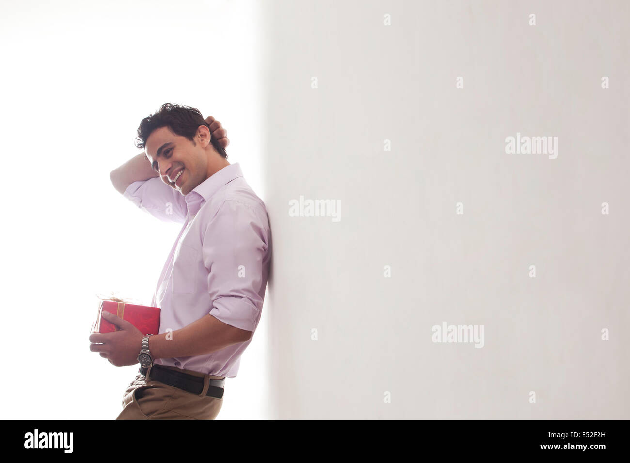 Uomo con un dono appoggiata contro la parete Foto Stock