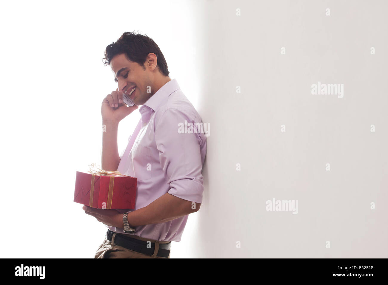 Uomo con un regalo a parlare su un telefono mobile Foto Stock