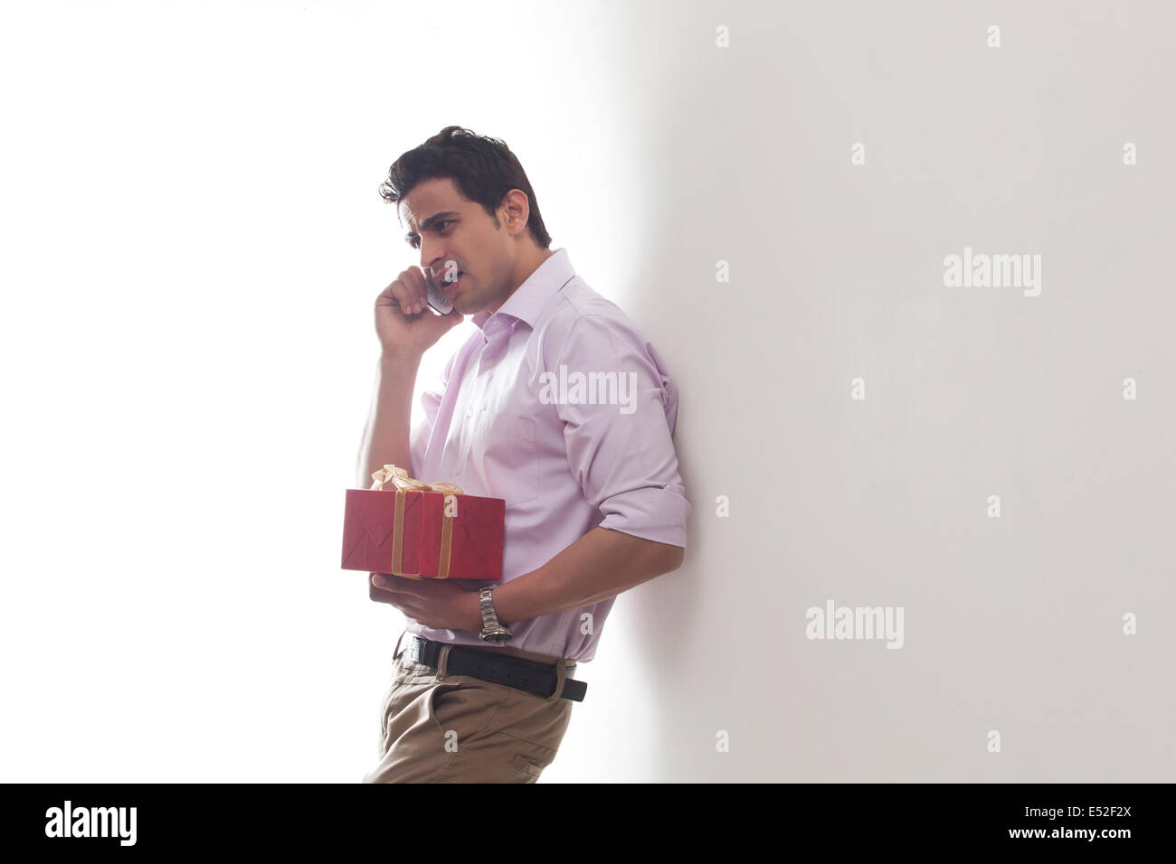 Uomo con un regalo a parlare su un telefono mobile Foto Stock