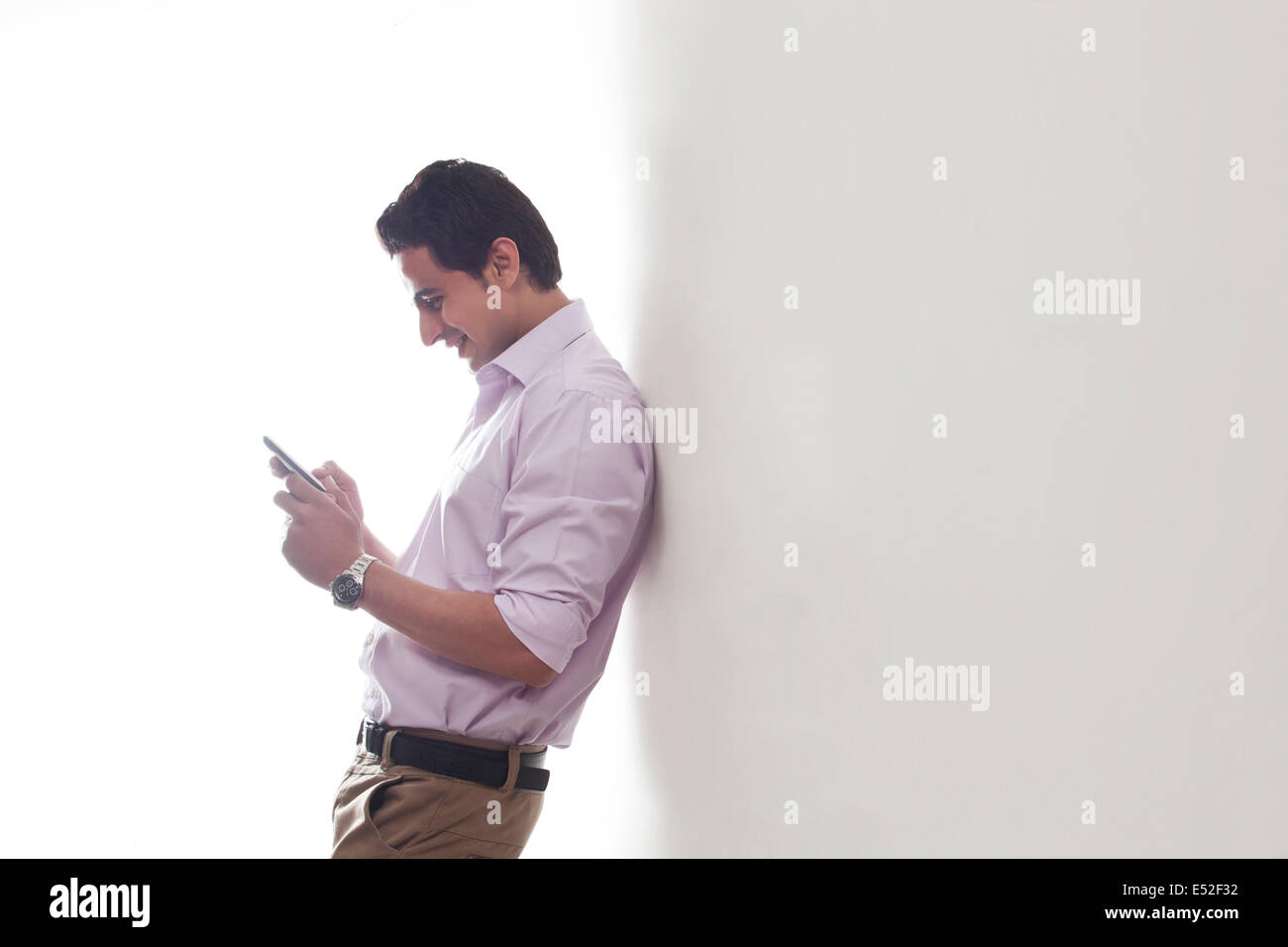 Uomo appoggiato contro una parete la lettura di un sms Foto Stock