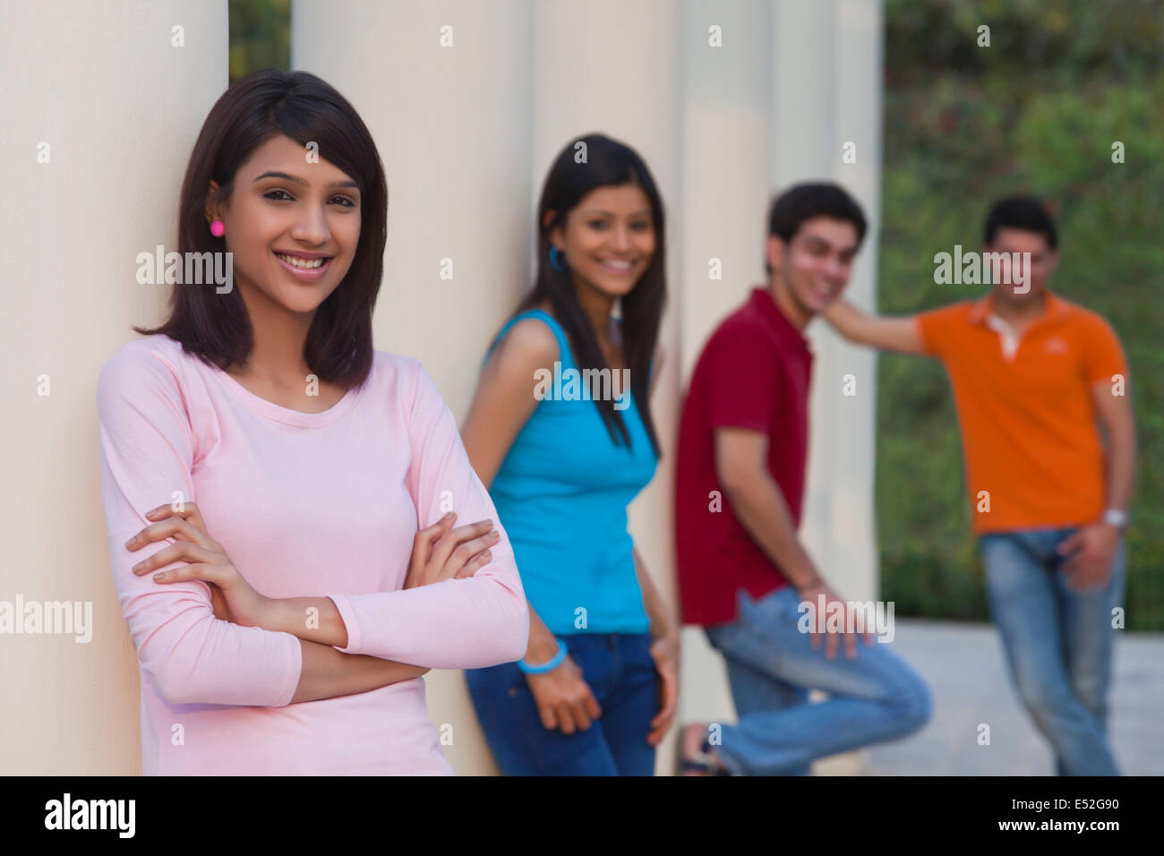 Ritratto di donna felice e amici che poggiano su colonne all'aperto Foto Stock