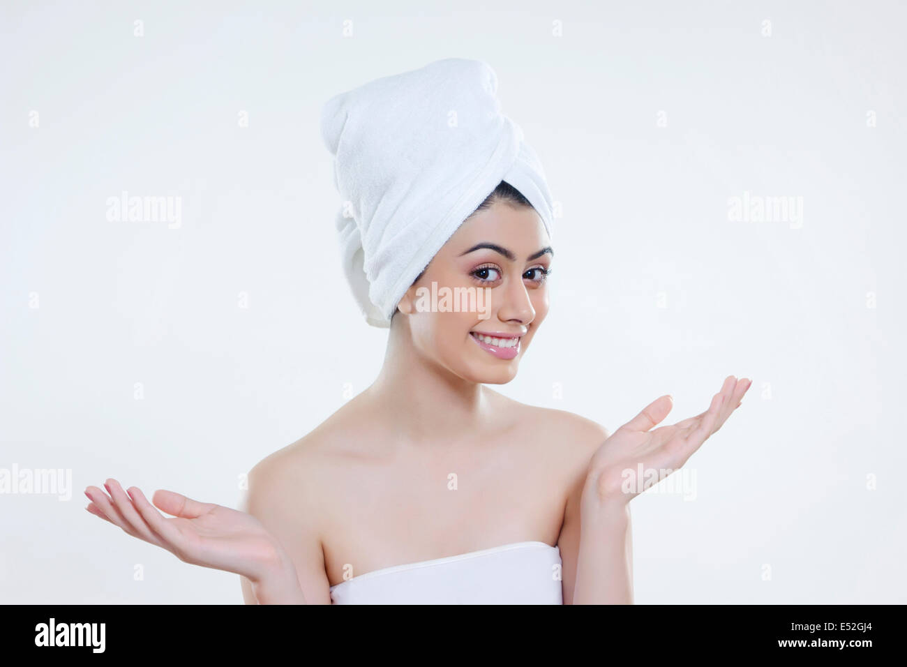 Ritratto di giovane donna avvolta in asciugamano gesticolando contro uno sfondo bianco Foto Stock