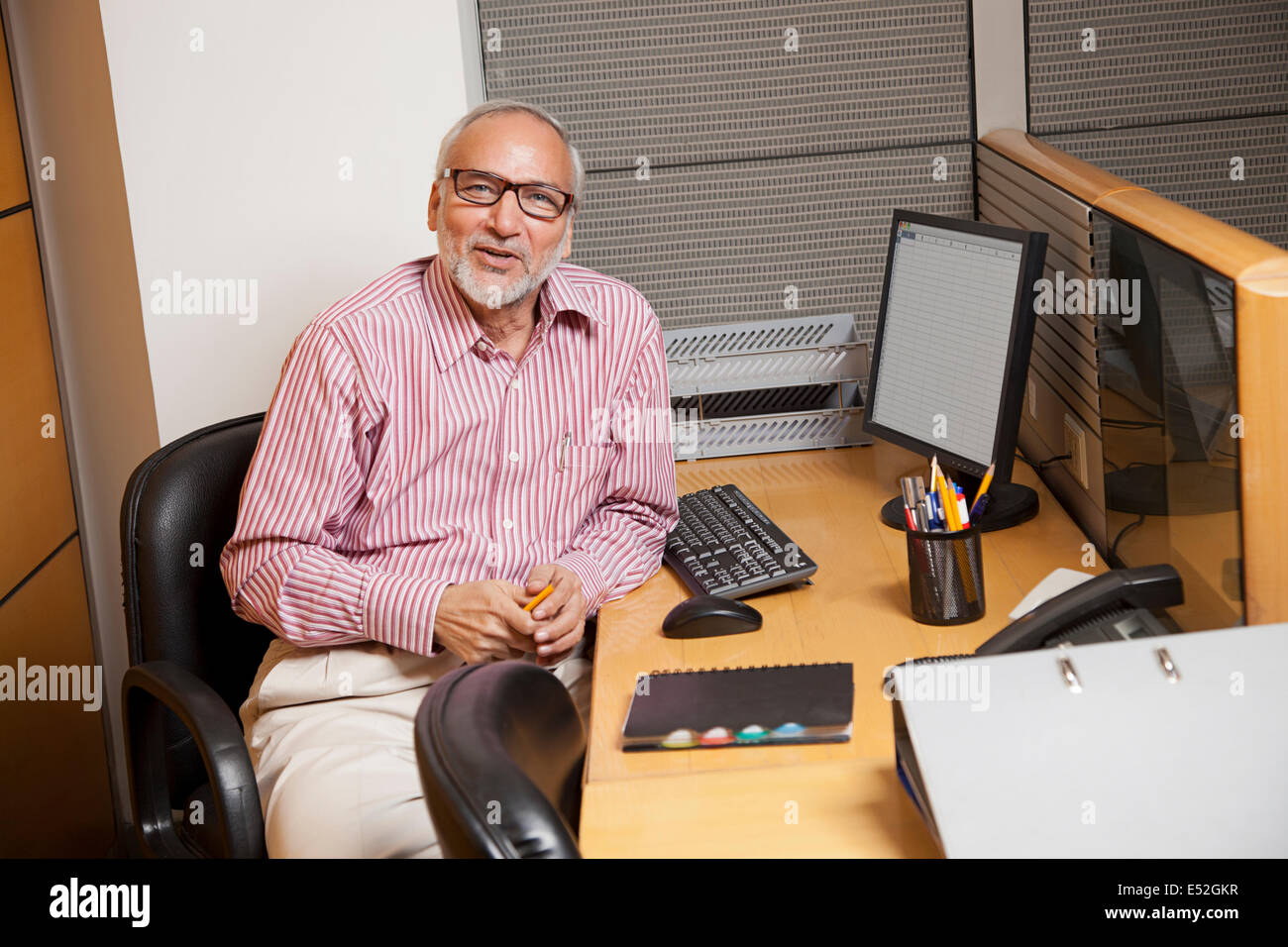 Ritratto di un senior business executive seduto alla sua postazione di lavoro Foto Stock