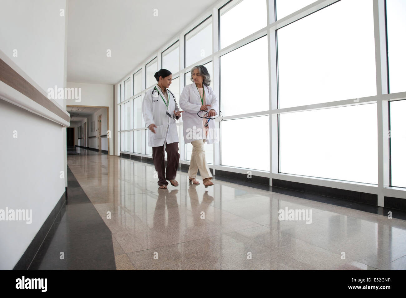 Due medici in discussione camminando giù il corridoio Foto Stock