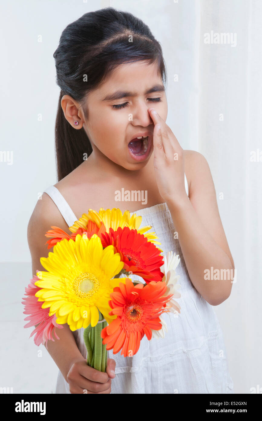 Bambina con fiori attorno a starnutire Foto Stock