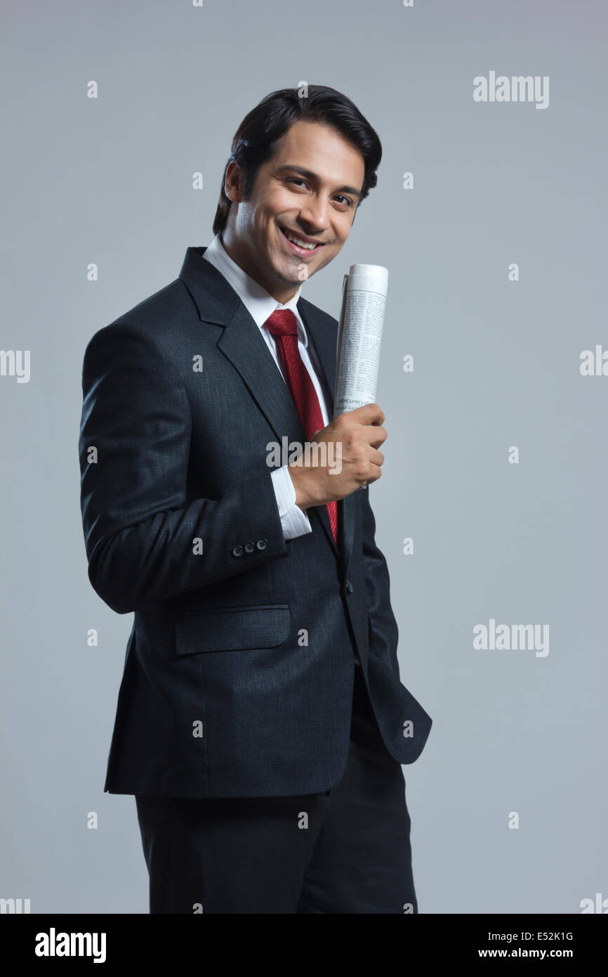 Ritratto di imprenditore sorridente azienda giornale su sfondo grigio Foto Stock