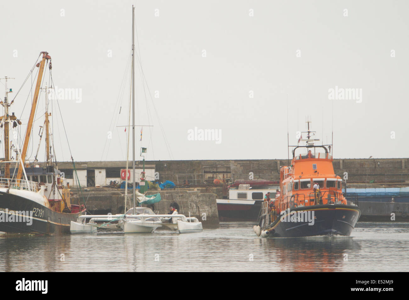 Newlyn, UK. 18 Luglio, 2014. La scialuppa di salvataggio Penlee stoppa 30 piedi di trimarano Newlyn in porto dopo le tempeste overnigh Credit: © Ashley Hugo/Alamy Live News Foto Stock