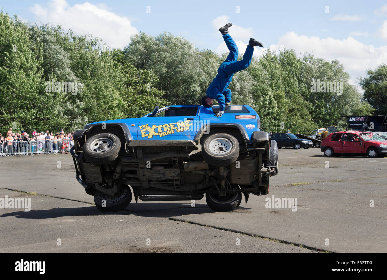 Stunt guida su due ruote con passeggero facendo headstand. Foto Stock