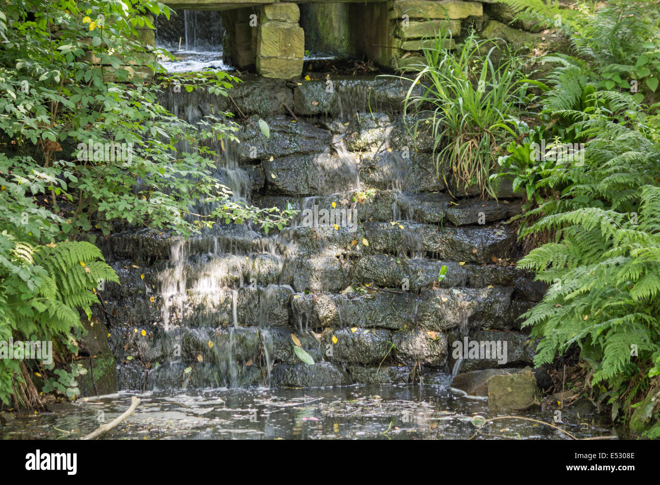 Una cascata di pietra in un parco in una giornata di sole Foto Stock