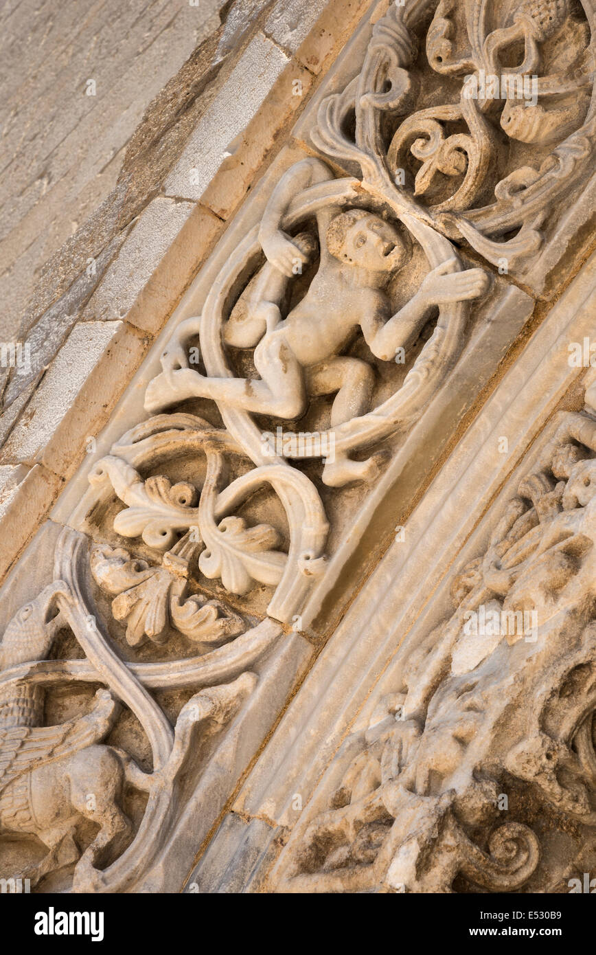 Dettaglio di un uomo con un oca sul romanico scolpito surround per le porte del XII secolo cattedrale romanica a Tran Foto Stock