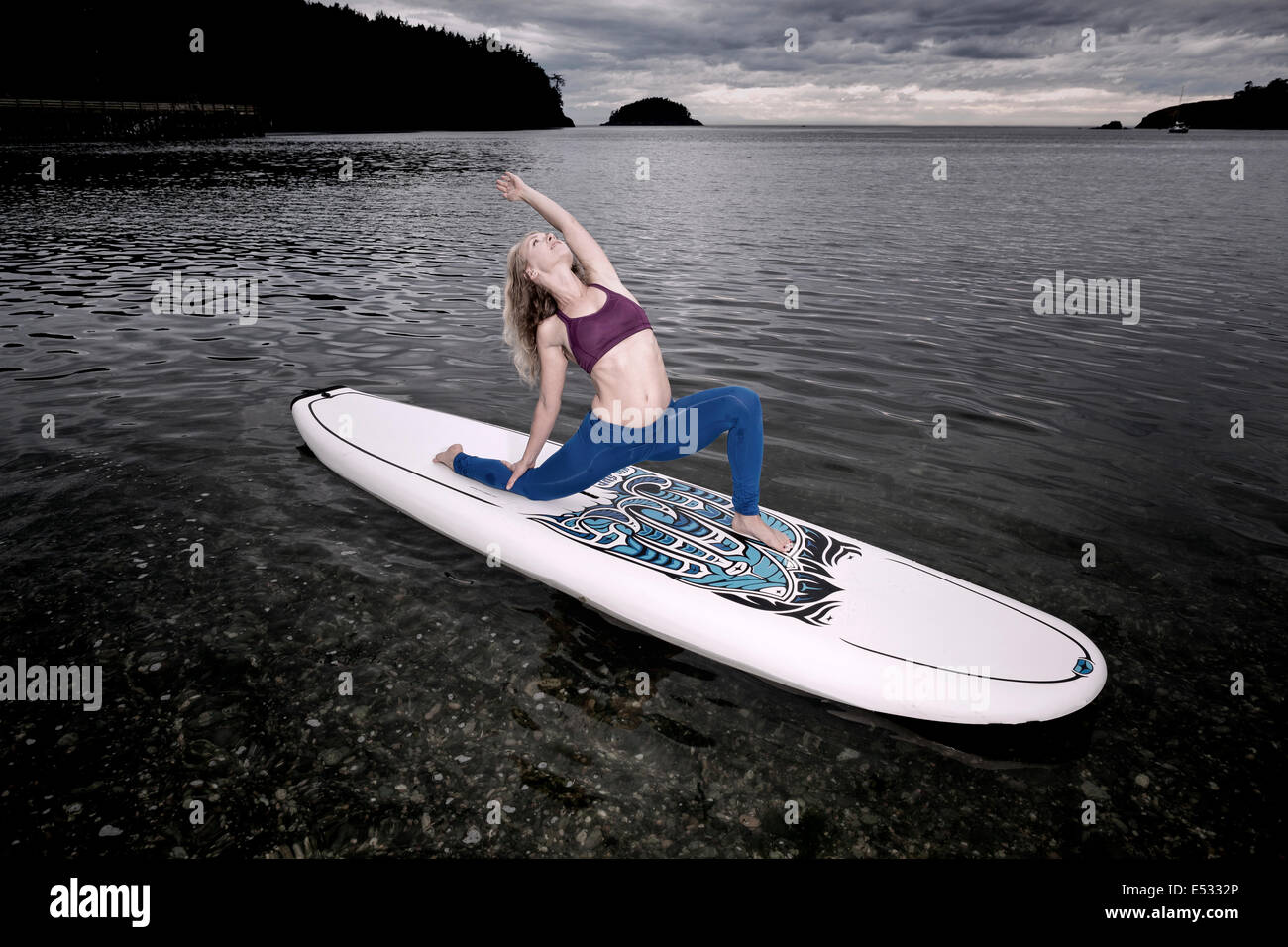 WASHINGTON - istruttore yoga Carly Hayden il riscaldamento su un SUP, (stand up paddle board), in Bowman Bay. Foto Stock