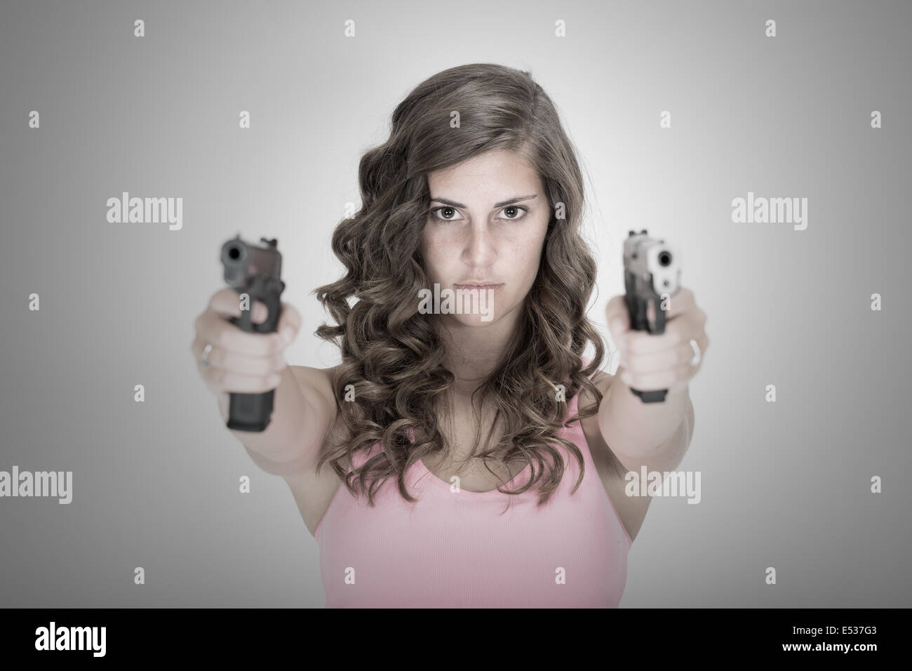 Giovane ragazza che puntano a due pistole direttamente a voi Foto Stock