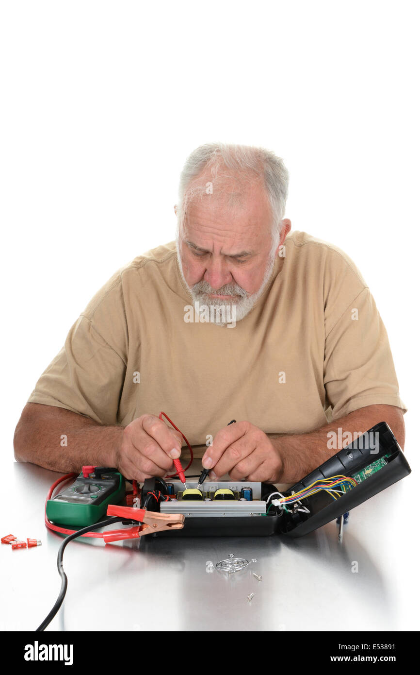 Primo piano di un aggiustatore utilizzando un voltmetro per testare i componenti di un dispositivo elettrico. Il tecnico sta guardando in giù al suo w Foto Stock