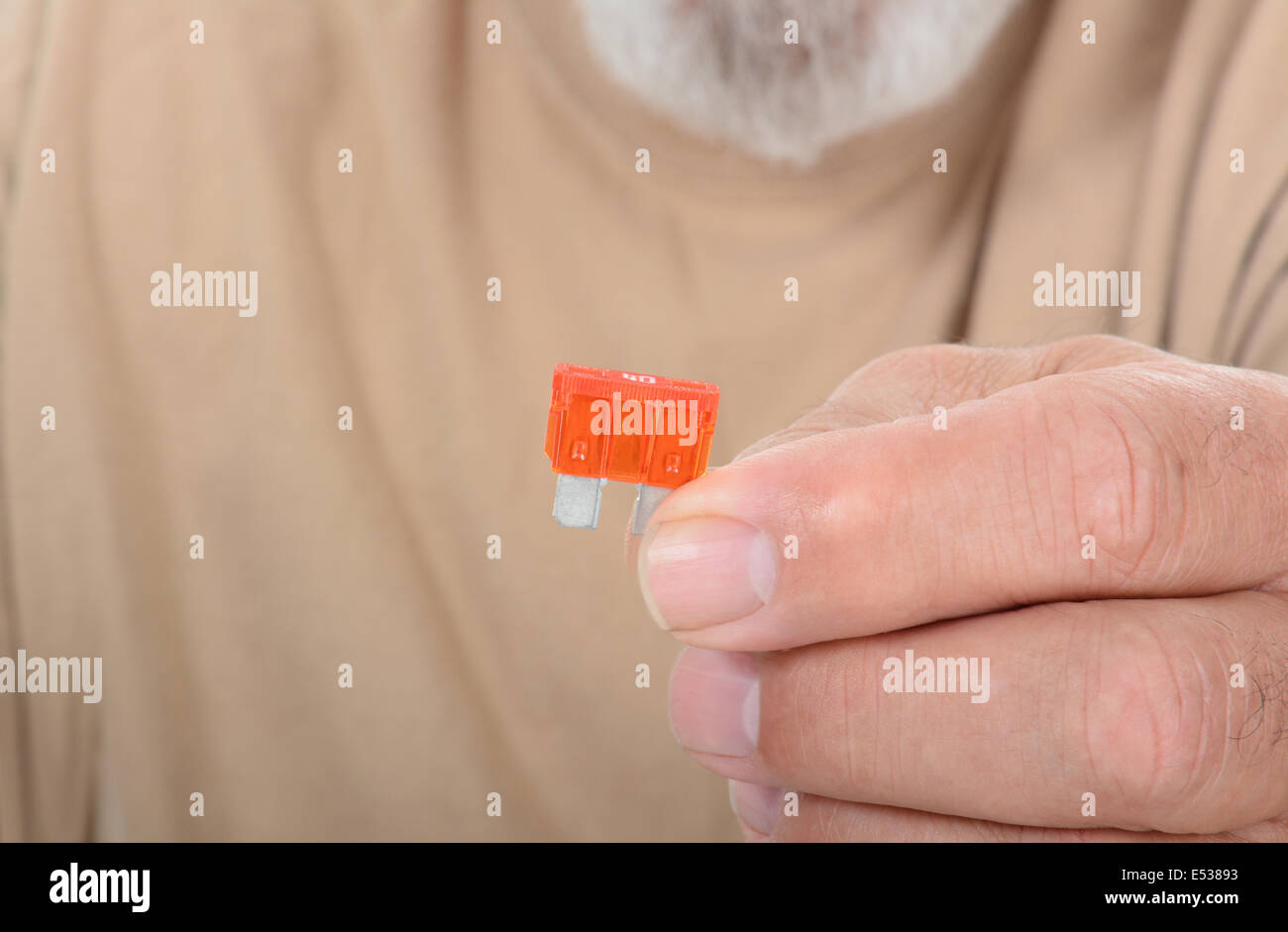 Primo piano di un tecnico tenendo un fusibile nella sua mano. L'uomo è irriconoscibile, con profondità di campo ridotta. Foto Stock