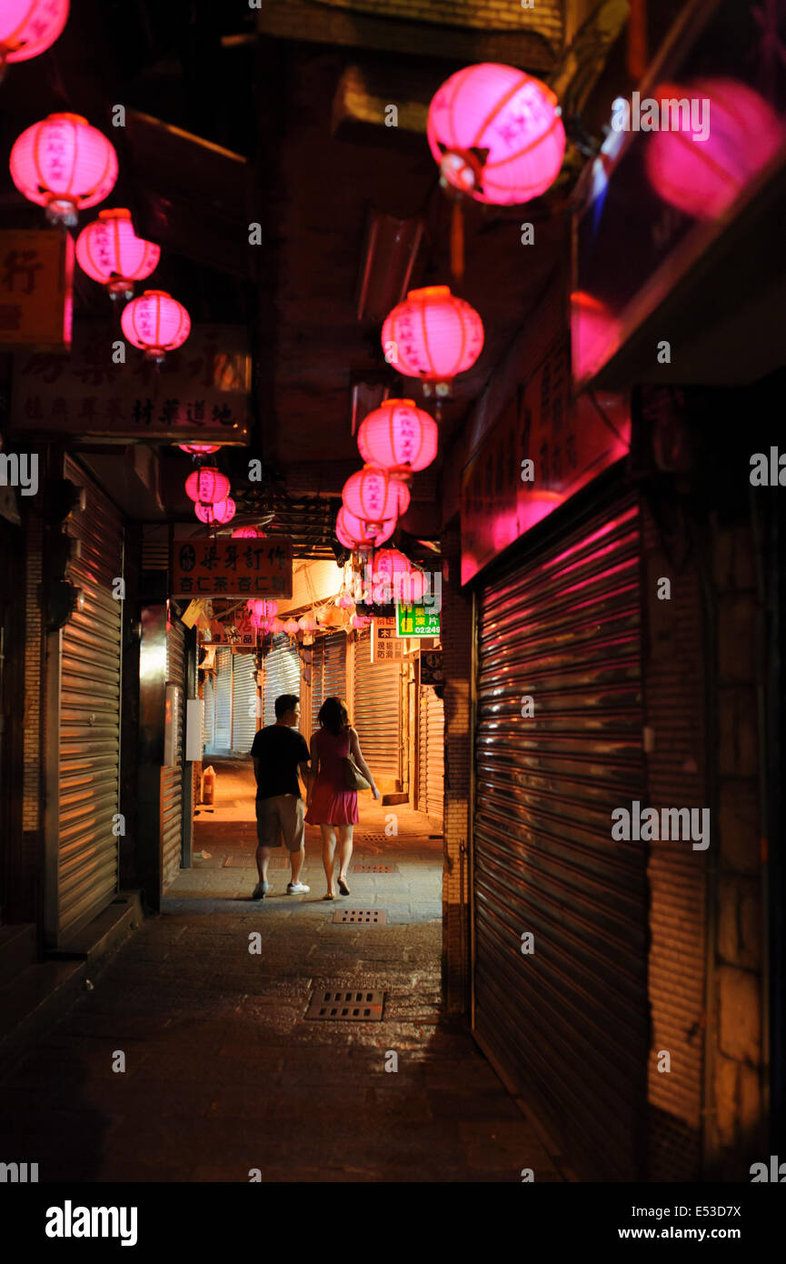 Un paio di amanti camminare mano nella mano in un vicolo lastricato all'alba, sotto romantico lanterne in Jiufen (九份), Taiwan. Foto Stock