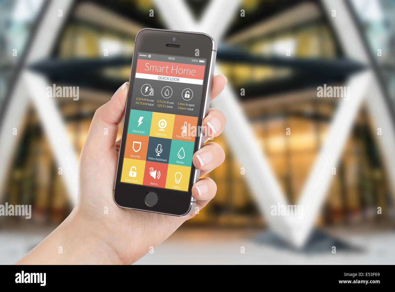 Femmina lato nero di contenimento mobile smart phone con smart home applicazione sullo schermo. Casa sfocata sullo sfondo. Per acc Foto Stock Femmina lato nero di contenimento mobile smart phone con smart home applicazione sullo schermo. Casa sfocata sullo sfondo. Per acc Foto Stock