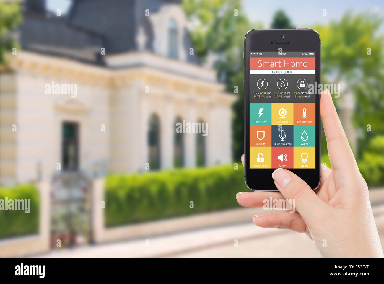 Femmina lato nero di contenimento mobile smart phone con smart home applicazione sullo schermo. Casa sfocata sullo sfondo. Per acc Foto Stock Femmina lato nero di contenimento mobile smart phone con smart home applicazione sullo schermo. Casa sfocata sullo sfondo. Per acc Foto Stock