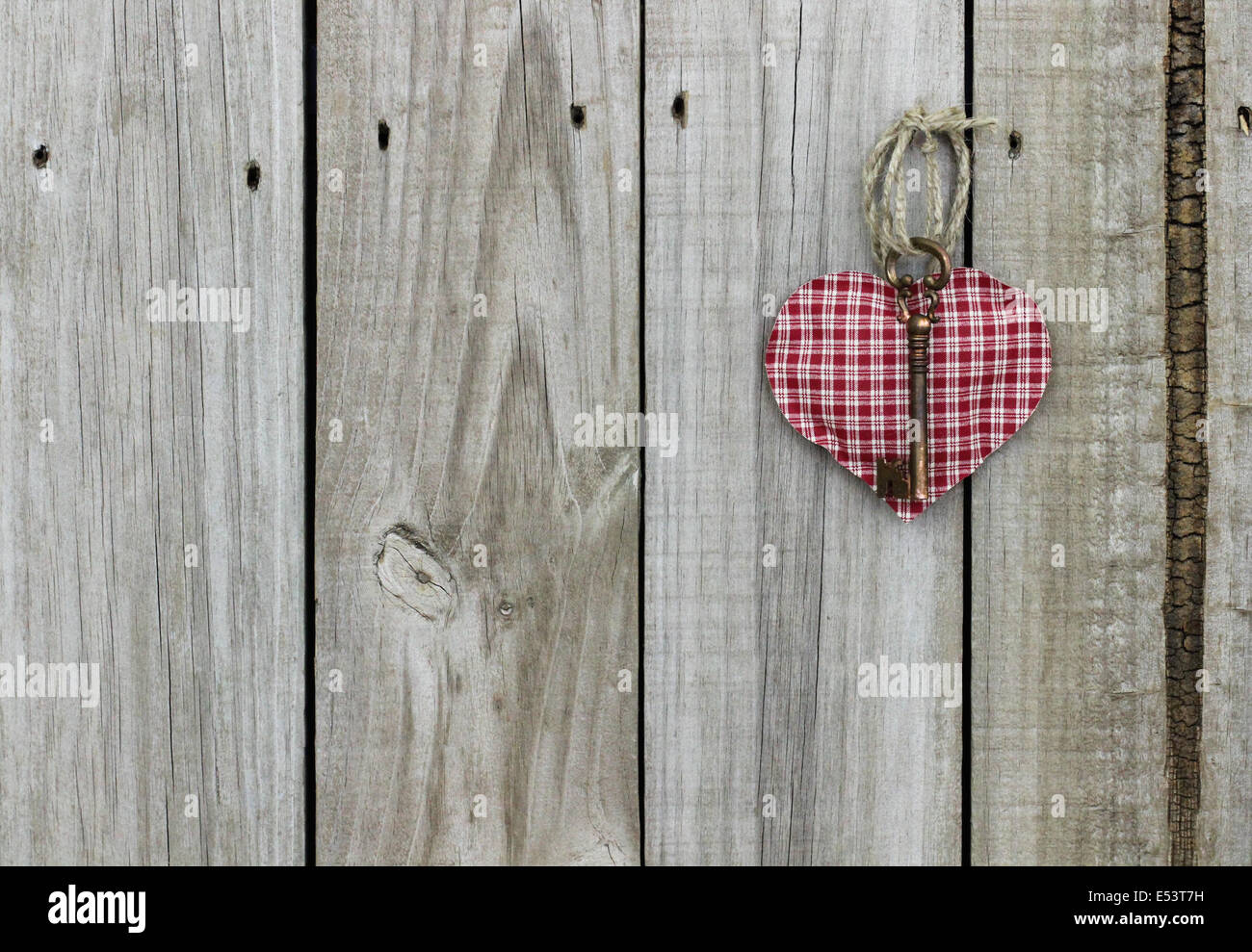 La chiave per il mio cuore; rosso a scacchi (plaid) Cuore con ottone chiave scheletro appeso su rustiche porta in legno Foto Stock