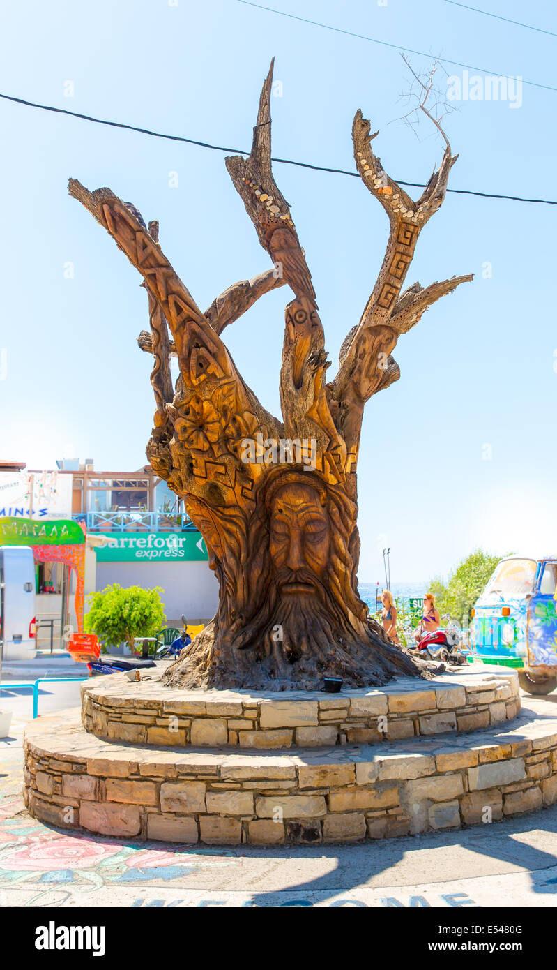 Albero con un volto scolpito sulla piazza di Matala, Grecia Creta. Foto Stock