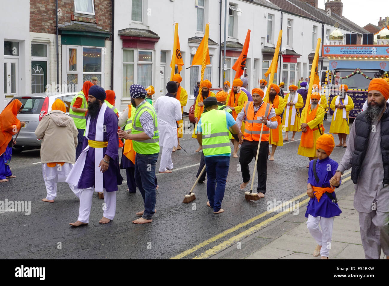 Middlesbrough, Regno Unito. Il 20 luglio, 2014. L annuale Nagar Kirtan Parade celebra la cultura Sikh nel nord-est dell' Inghilterra ha avuto luogo in Middlesbrough Cleveland UK oggi è domenica 20 luglio. Il corteo è guidato da cinque zafferano derubato gli uomini che portano un galleggiante che porta il Guru Granth Sahib i sikh la Sacra Scrittura. Membri della processione è a piedi nudi in ossequio alla scrittura così visualizzato. Essi sono preceduti da spazzatrici pulizia della strada. Questa immagine mostra il volontario street pulitori di fronte alla sfilata Credito: Pietro Giordano NE/Alamy Live News Foto Stock